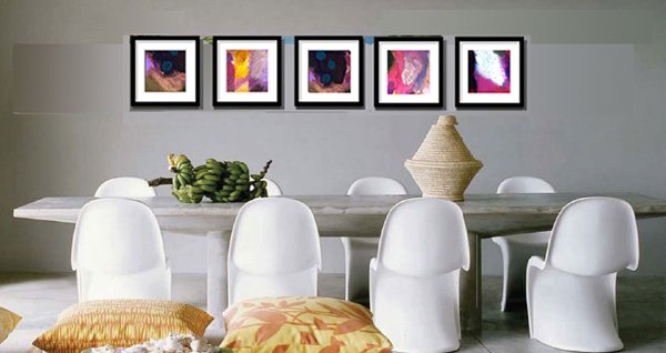 Series of five small abstract paintings in dark frames, each with different colour fields of purple, gold, teal and pink, hung above a dining table.
